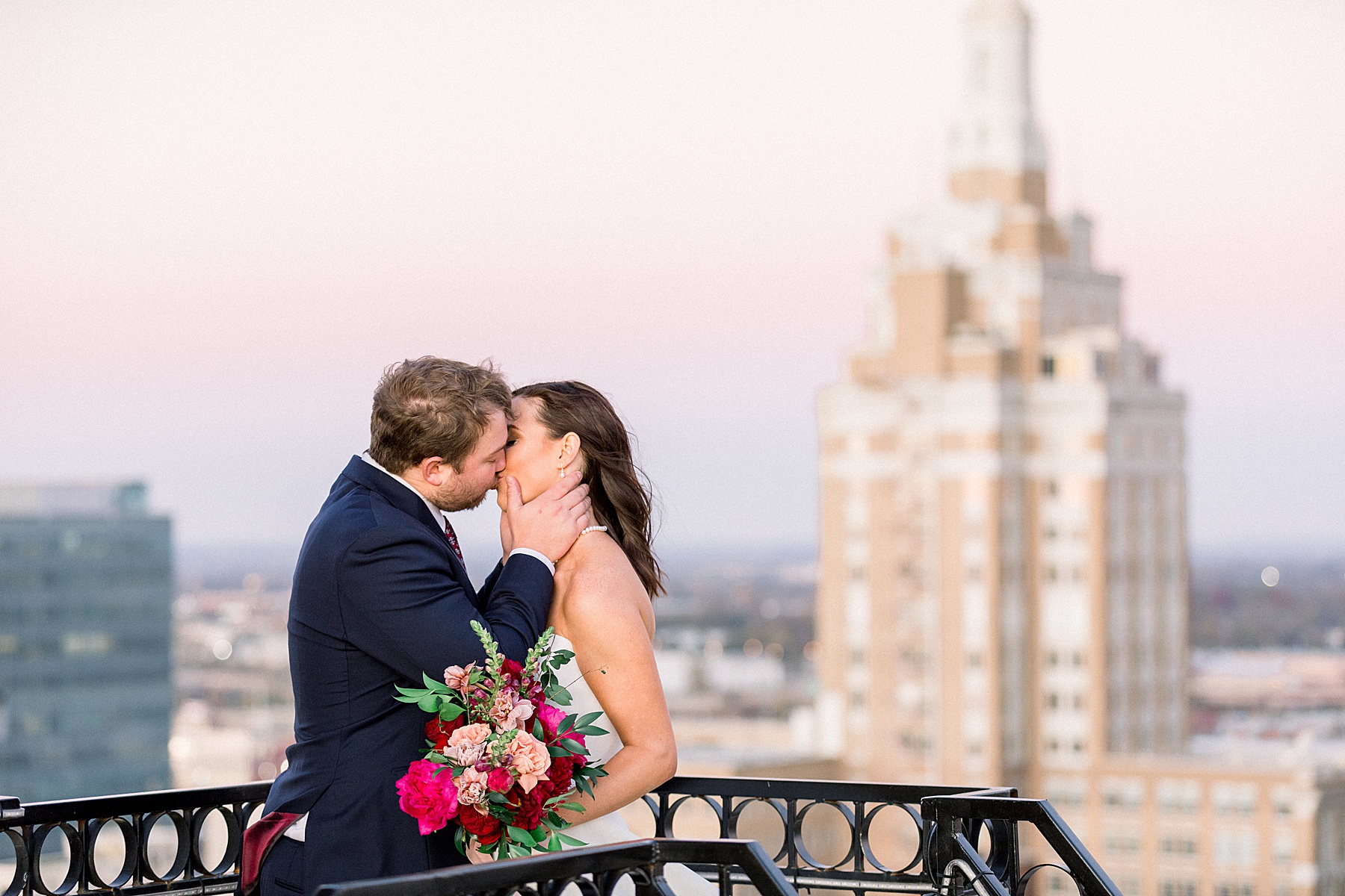 Bride and groom kiss on rooftop at The Mayo Hotel wedding
