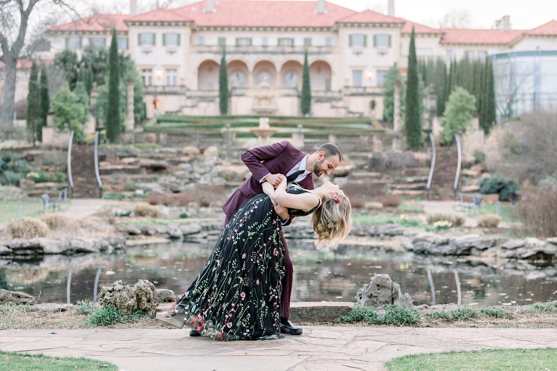 Guy dips girl in front of Philbrook Museum gardens engagement